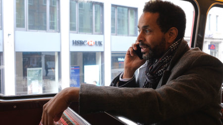 Businessman takes a phone call while riding in a bus - LONDON, ENGLAND - DECEMBER 15, 2018のeditorial素材