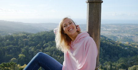 Young woman sits on the wall of Palace of Pena in Portugal - CITY OF LISBON - SINTRA. PORTUGAL -...