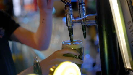 Draw a fresh Guinness beer in a pub - DUBLIN, IRELAND - APRIL 20, 2022