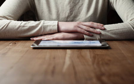 woman looking at  screen digital tablet over wooden tableの写真素材