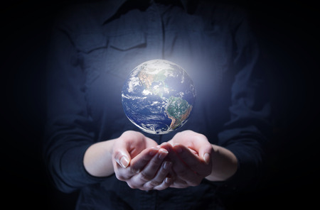 Businesswoman holding Earth planet in palm. Elements of this image are furnished by NASAの写真素材