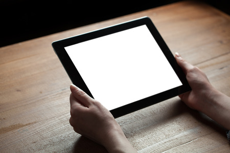 female hands holding digital tablet computer with isolated screen over old grey wooden background tableの写真素材