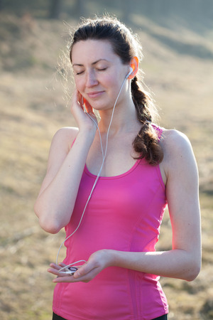Woman listening to mp3 player whilst running and wearing sports wearの写真素材