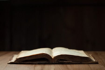 Image of an old Holy Bible on wooden background in a dark spaceの写真素材