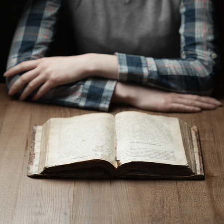 woman reading the bible in the darkness over wooden table