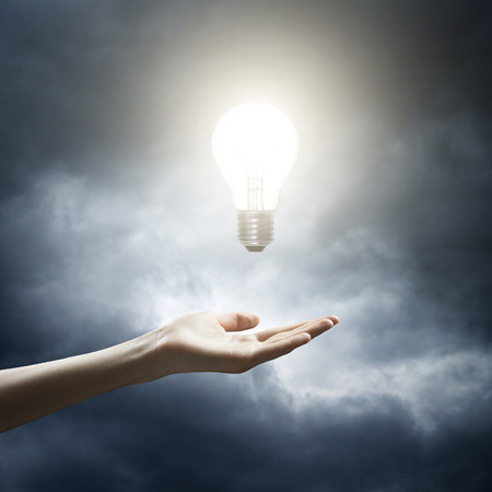 Woman holding a glowing lightbulb in her handの写真素材