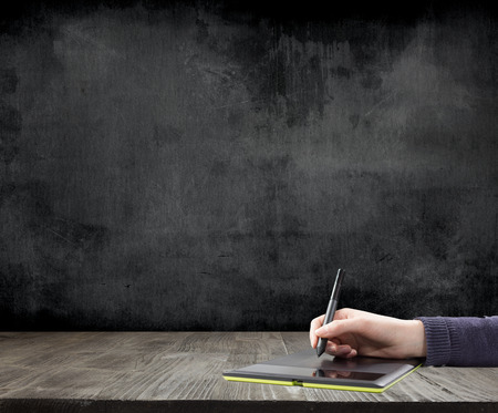 hand drawing a graph on the tablet with a blackboard on the backgroundの写真素材