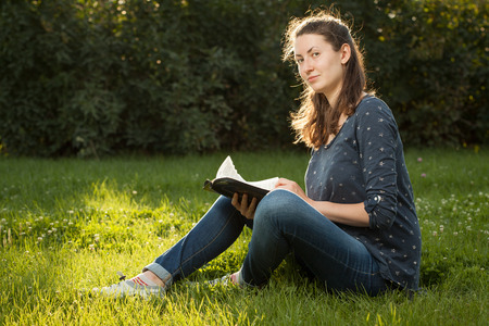 Teen girl reading the Bible sitting outdoorsの写真素材