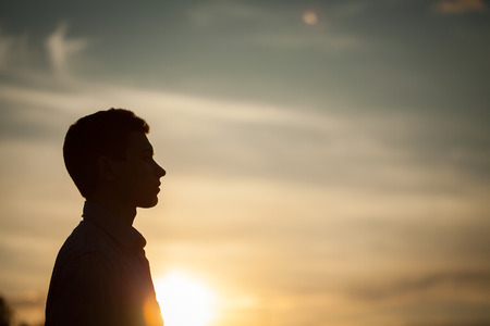 Silhouette of boy on sea sunset