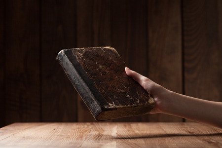 woman holding the bible in the darkness over wooden tableの写真素材