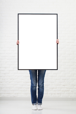woman with blank poster on wall backgroundの写真素材