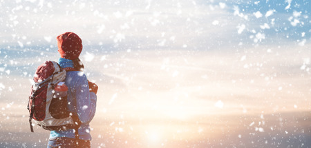 Hiker girl with backpack  looking to the horizon with the snowの写真素材