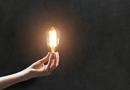 hand holding Light bulb on blackboard backgroundの写真素材