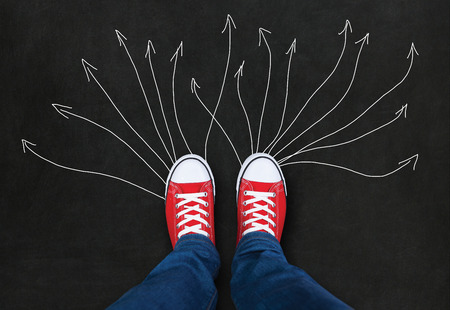 Feet wearing red shoes on black background with arrows. choice concept
