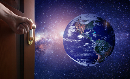 hand opens empty room door to Planet earth from the space. Some elements of this image furnished by NASAの写真素材