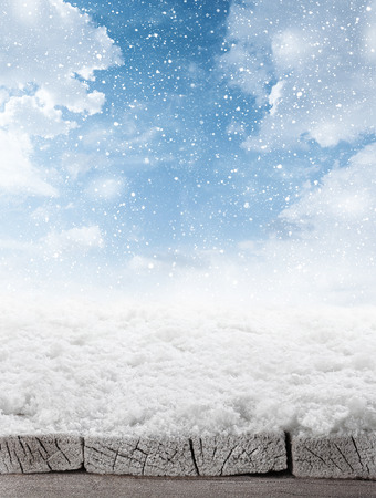 empty winter background of wooden table and sky with falling snowの写真素材