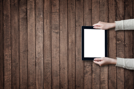 female hands holding digital tablet computer with isolated screen over old grey wooden background tableの写真素材