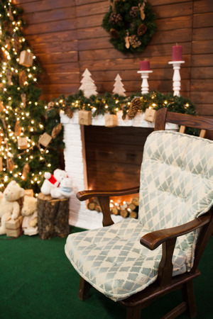 Christmas holiday background of wooden chair against decorated Christmas tree and fireplaceの写真素材