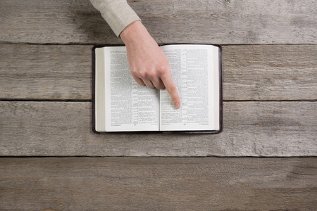 woman hands on bible. she is reading and praying over bible over wooden tableの写真素材