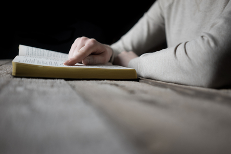 woman reading the bible in the darkness over wooden tableの写真素材