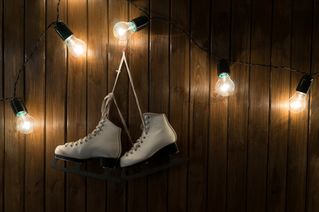 ice skates against an weathered wooden wall with lightbulbsの写真素材