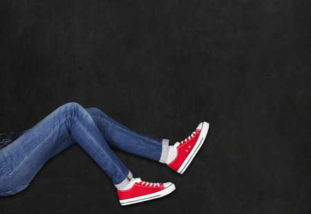 Feet wearing red shoes on black background with space for textの写真素材