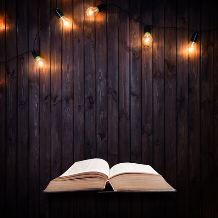 Opened book on a wooden background with Light bulbsの写真素材