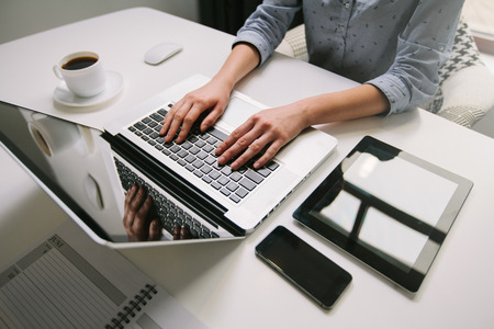 woman working on laptop on wooden desk in officeの写真素材