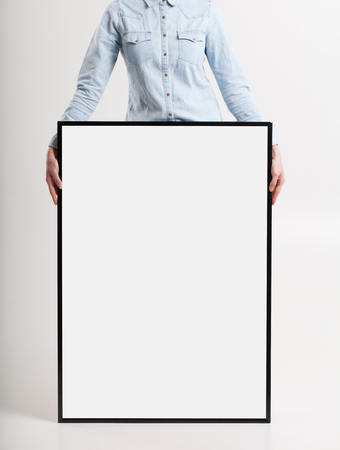 woman with blank poster on wall backgroundの写真素材