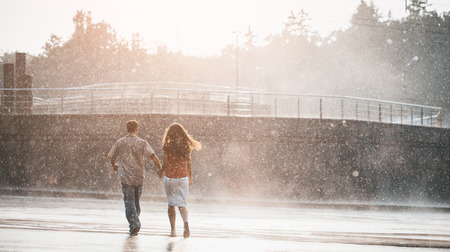 couple walking under summer rainの写真素材
