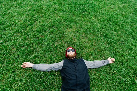 Hipster boy wearing sunglasses and lying on grassの写真素材