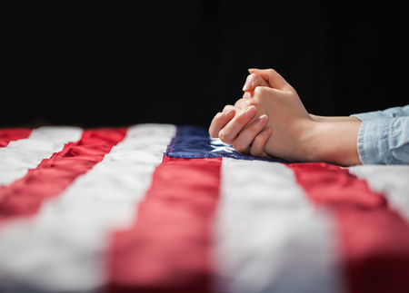 Hands praying over american flagの写真素材