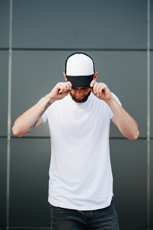Hipster wearing white blank t-shirt and a baseball cap with space for your logoの写真素材