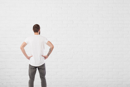 Man looking at aged paint white brick wall backgroundの写真素材