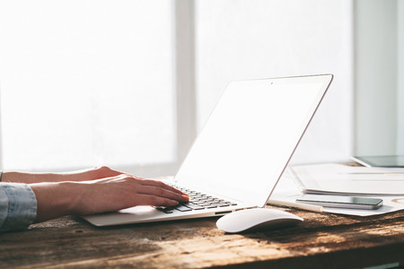 Woman working on a laptop and tablet pc indoor on a wooden standing desk