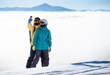 Skiers taking picture of themselves with smartphone over a mountainの写真素材