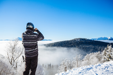 Man in winter clothes taking a selfie with mountainsの写真素材