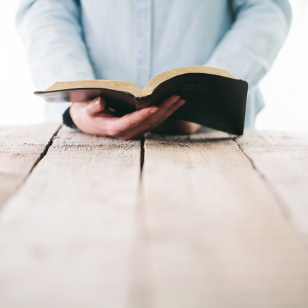 Bible in hands of a woman. She is readind and praying over itの写真素材