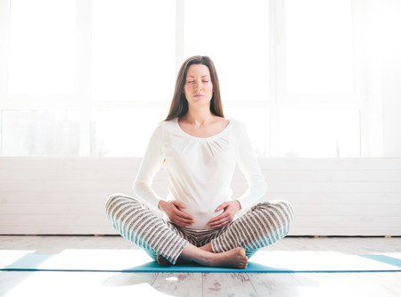 Pregnant woman doing yoga at homeの写真素材