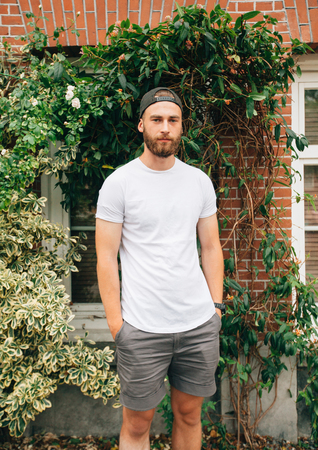 Hipster handsome male model with beard  wearing white blank  t-shirt with space for your logo or design in casual urban styleの写真素材