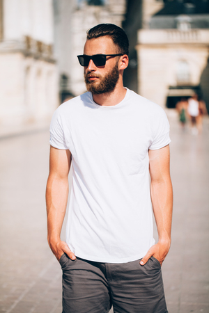 Hipster handsome male model with beard wearing white blank t-shirt with space for your logo or design in casual urban styleの写真素材