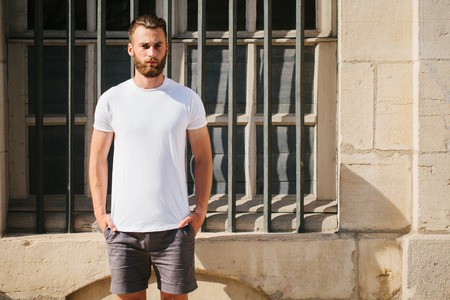 Hipster handsome male model with beard wearing white blank t-shirt with space for your logo or design in casual urban styleの写真素材