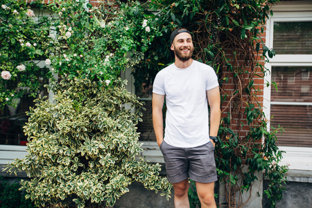 Hipster handsome male model with beard  wearing white blank  t-shirt with space for your logo or design in casual urban styleの写真素材