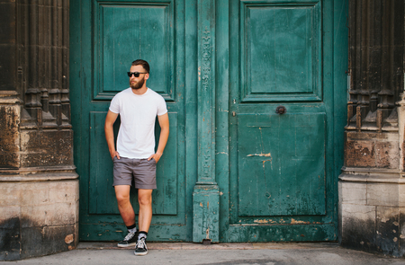 Hipster handsome male model with beard wearing white blank t-shirt with space for your logo or design in casual urban styleの写真素材