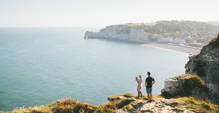 Love couple hiking and taking picture of Etretat cliffs and Atlantic ocean in Etretat, Franceの写真素材