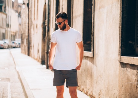 Hipster handsome male model with beard wearing white blank t-shirt with space for your logo or design in casual urban styleの写真素材