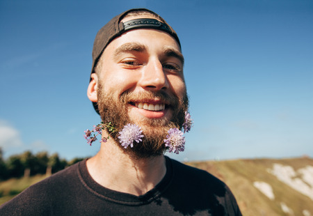 Hipster handsome male model with beard decorated with wild flowersの写真素材