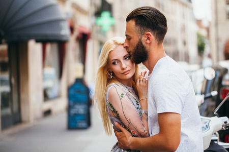 Blonde girl and Hipster handsome man with beard hugging and kissing on the city streetsの写真素材