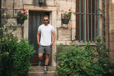 Hipster handsome male model with beard wearing white blank t-shirt with space for your logo or design in casual urban styleの写真素材