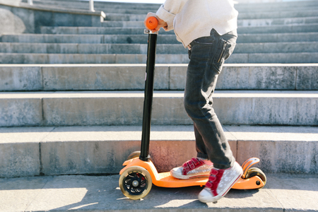 Kid riding a scooter in the cityの写真素材